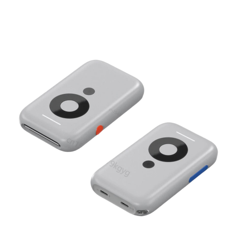 Two small, rectangular gadgets with smooth gray surfaces featuring circular black patterns and small multicolored accents (one red and one blue). The objects have a compact, minimalist design with rounded corners and appear to be XREAL Air AR Glasses - Nreal Portable 3D HD by HeadphoneHeat.