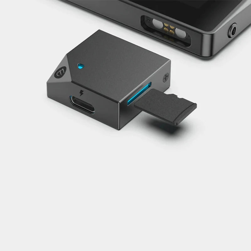 A close-up image of the ELLIPAL Titan Mini security Cold Hardware Crypto Wallet from the brand HeadphoneHeat, featuring a USB-C port, a microSD card slot with a microSD card partially inserted, and a blue LED indicator. The wallet is positioned next to another electronic device.