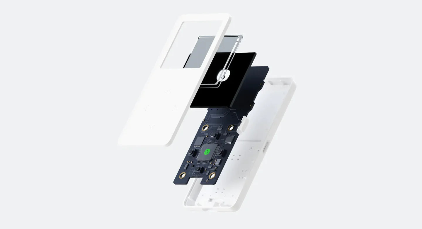 An exploded view of the HeadphoneHeat OneKey Mini Offline Crypto Wallet, showcasing its internal components. Visible parts include a white outer casing, a small display screen, a black circuit board with electronic elements, and additional internal layers that fit into the outer shell. All parts are floating apart in alignment.