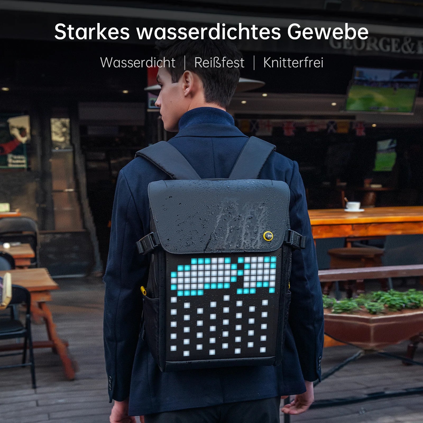 A person is sporting the HeadphoneHeat DIVOOM Pixoo M Backpack Men 15 Inch, featuring a brilliant 16 × 16 RGB LED screen displaying blue and white blocks. The backdrop includes the charming outdoor seating of a café. Across the top, text highlights "Starkes wasserdichtes Gewebe," accompanied by icons indicating waterproof, tear-resistant, and wrinkle-free features.