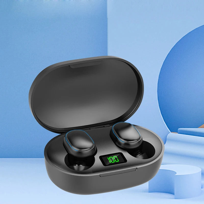 A black case of the E7s TWS Earbuds Bluetooth by HeadphoneHeat is displayed against a minimalist blue background, featuring blue shapes and stair-like structures. The open case reveals two in-ear True Wireless Earphones with active noise cancellation. A green digital display on the case shows "100," indicating a full battery charge.