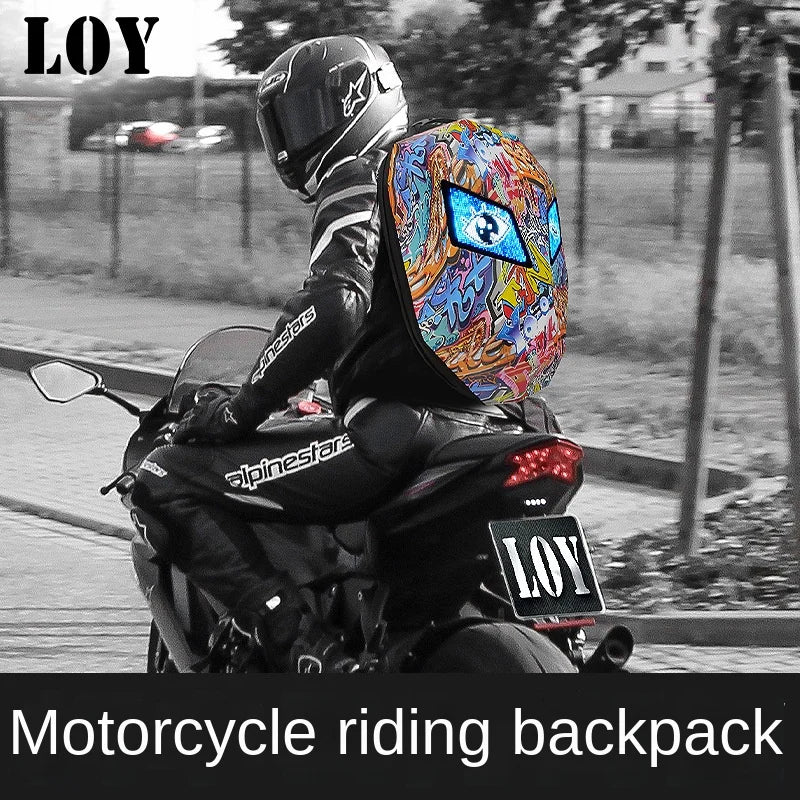 A motorcyclist wearing a helmet and an LED Snakeskin Backpack by HeadphoneHeat rides a motorcycle on the road. The unisex backpack features a vibrant design with various patterns and an eye symbol. The bike's license plate and the image have the text "LOY." Below, there's the phrase "Motorcycle riding backpack.