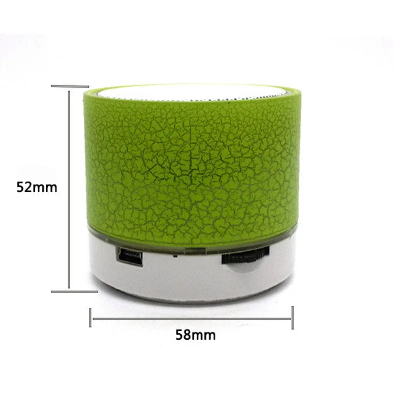 A XMSJ A9 Mini Portable Speaker LED and Subwoofer in green, offered by HeadphoneHeat, features a cracked texture design and measures 52mm in height and 58mm in diameter. The base is equipped with ports for connectivity.