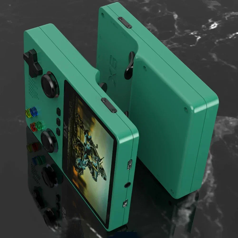 Two teal EVANOVM X6 Retro Game Consoles from HeadphoneHeat are displayed against a dark marble background. One screen showcases a game with a robot figure. The consoles feature joysticks, buttons, and side ports, and they boast over 10 classic arcade games for endless fun.