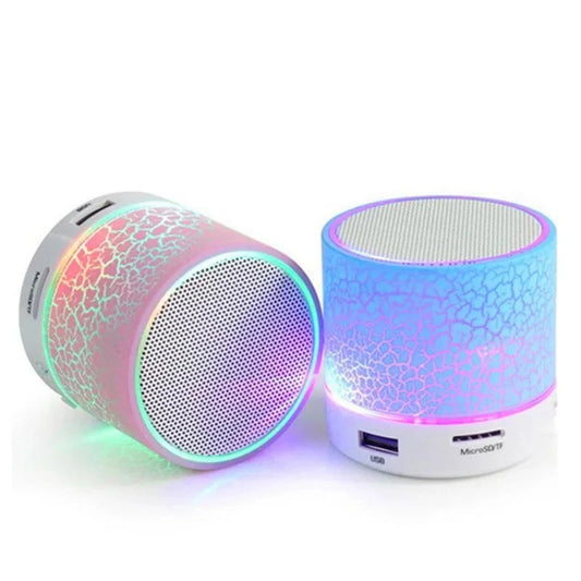 Two small cylindrical XMSJ A9 Mini Portable Speakers by HeadphoneHeat, one in pink and the other in blue, both showcasing a crackled finish and featuring vibrant multicolored LED lights. These compact speakers are equipped with USB and MicroSD ports at their base.