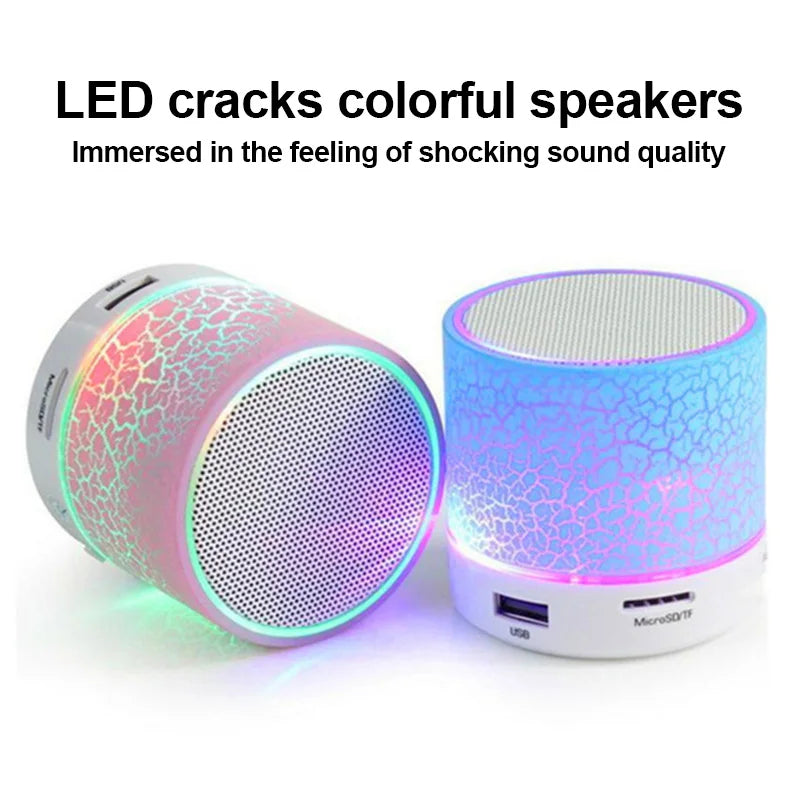 Two XMSJ A9 mini portable speakers by HeadphoneHeat, featuring LED crackle designs in pink and blue, emit glowing lights. The text above reads, "LED cracks colorful speakers - Immersed in the feeling of shocking sound quality.