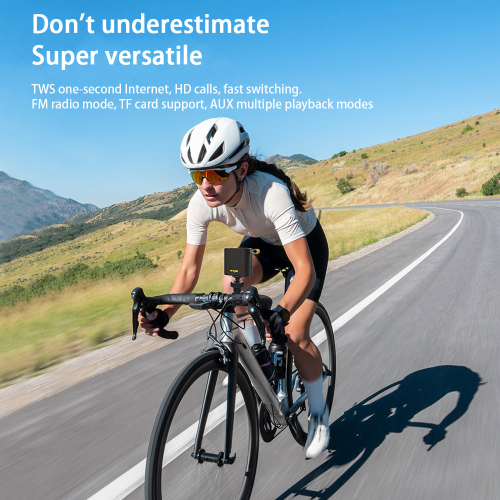 A cyclist rides on a scenic mountain road under a blue sky, with a smartphone and the W-King D2 Bluetooth Speaker from HeadphoneHeat mounted on the handlebars. Text above highlights features like TWS Internet, HD calls, wireless connectivity, FM radio mode, and more.